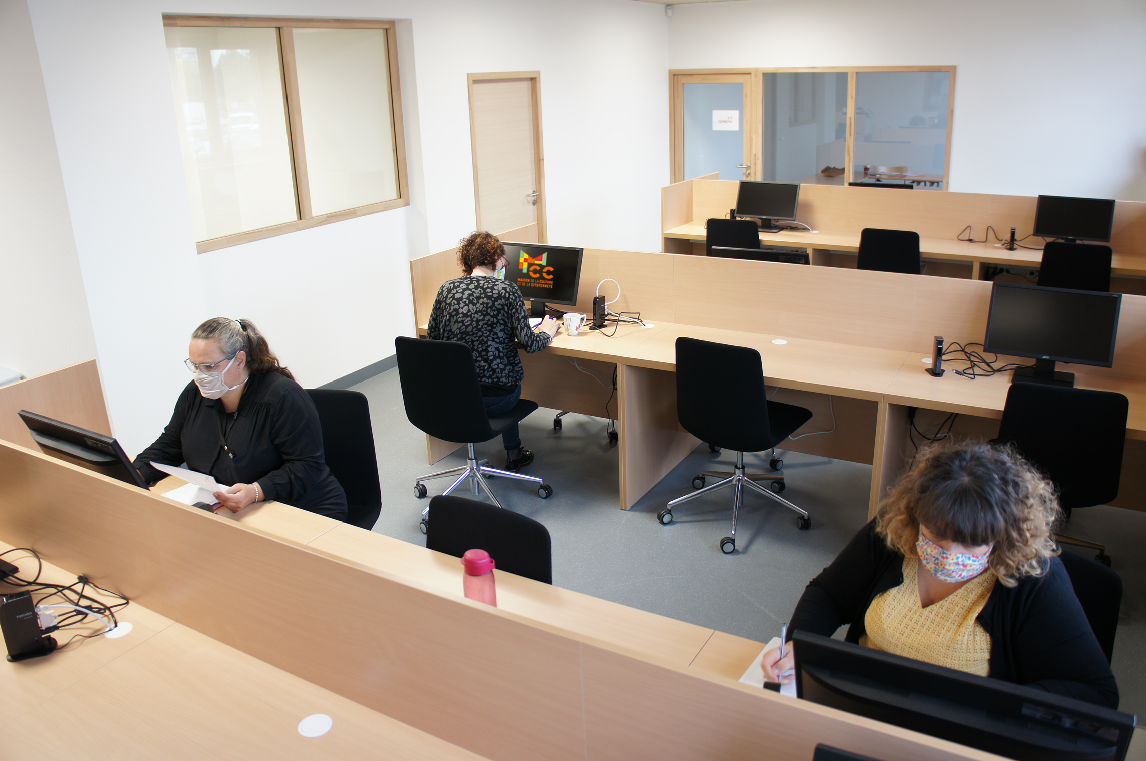 Trois personnes utilisent les locaux et ordinateurs de l'espace Coworking à la MCC