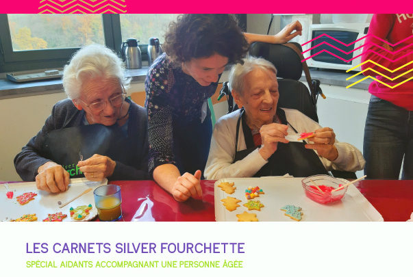 une animatrice se penche vers deux dames âgées qui font un atelier pâtisserie ; elles décorent des biscuits