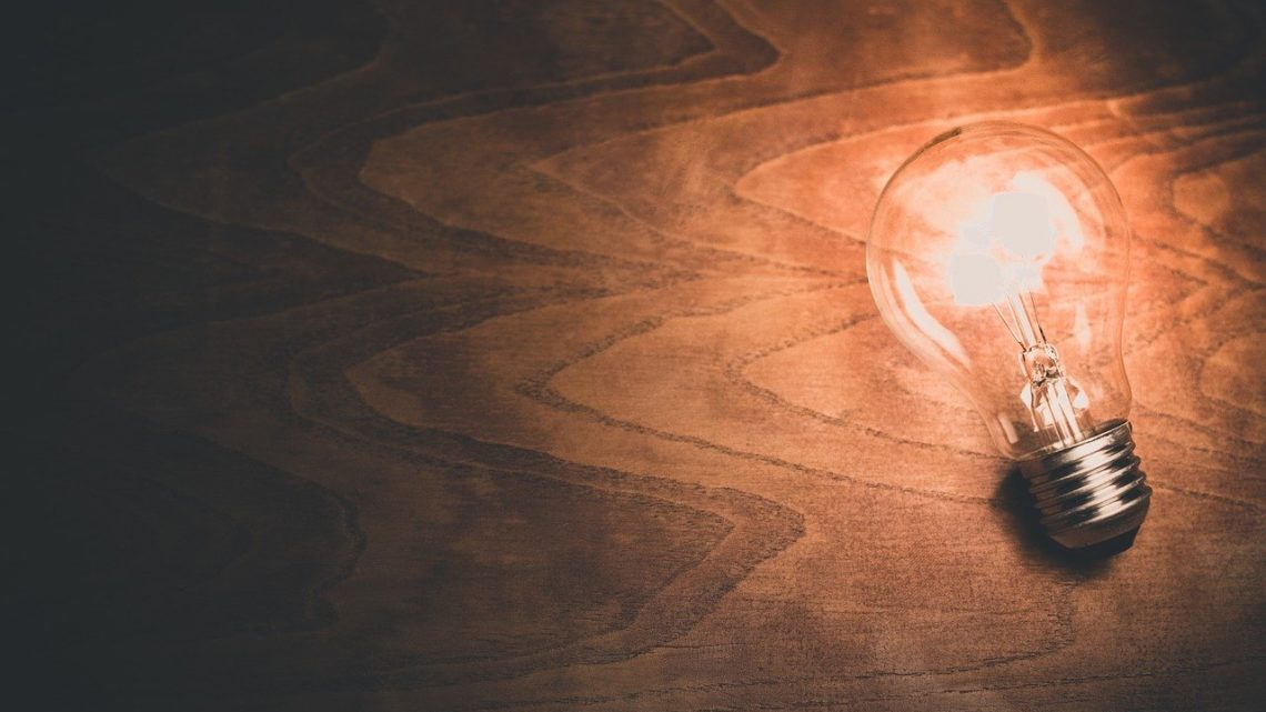 une ampoule allumée sur une table en bois projette sa lumière