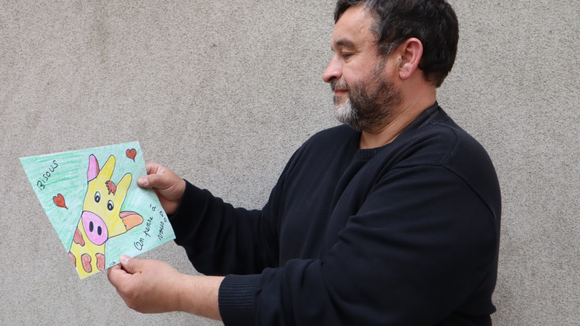 Ludovic Orge, président de Pèse Plume, regarde un dessin de girafe fait par un enfant