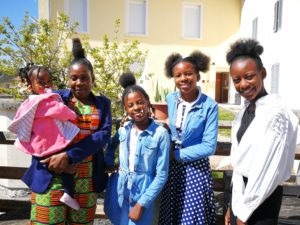 une mère et ses 4 filles, d'origine africaine, sourient devant un bâtiment