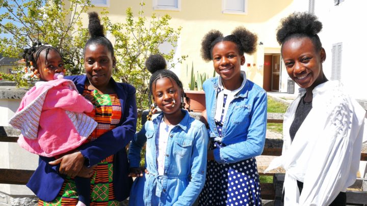 une mère et ses 4 filles, d'origine africaine, sourient devant un bâtiment