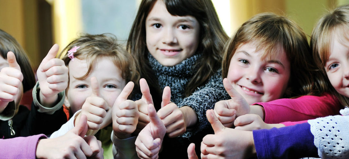 un groupe de jeunes filles alignées regardent la caméra, sourient et lèvent le pouce dans un signe positif