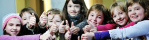 un groupe de jeunes filles alignées regardent la caméra, sourient et lèvent le pouce dans un signe positif