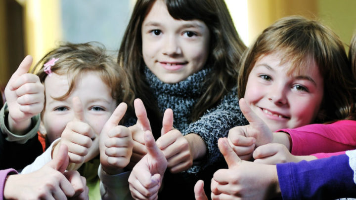 un groupe de jeunes filles alignées regardent la caméra, sourient et lèvent le pouce dans un signe positif