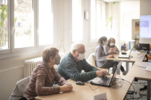 par groupes de deux, les participants de l'atelier numérique s'exercent : on voit un homme taper sur son clavier tandis que sa coéquipière l'observe.