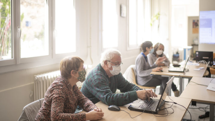 par groupes de deux, les participants de l'atelier numérique s'exercent : on voit un homme taper sur son clavier tandis que sa coéquipière l'observe.