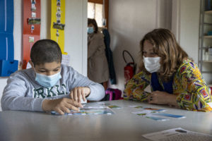 Un enfant joue avec des cartes tandis qu'une dame l'observe et l'accompagne.