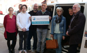 un groupe de personnes se tiennent devant un van, et tiennent une pancarte où on peut lire "Asso FenêtreS, tel 09 54 92 39 73"