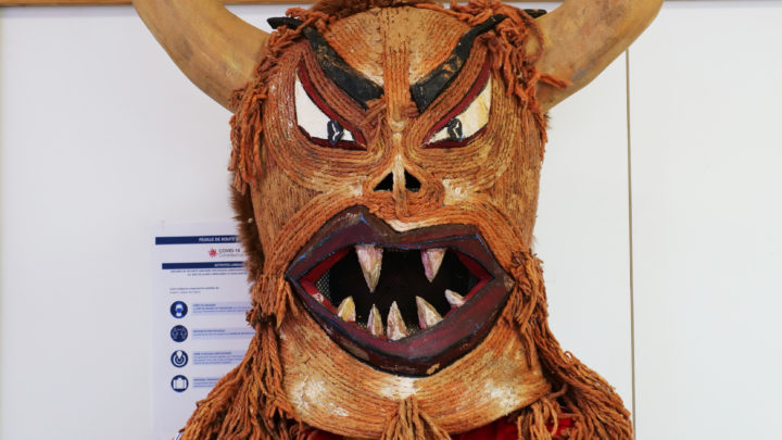 Une personne porte un masque de "monstre", poilu, cornu et avec de grandes dents pointues, pour le projet Festum