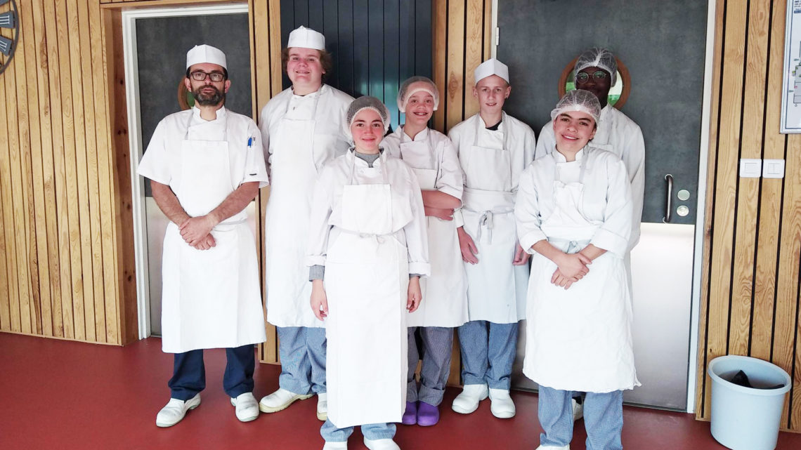 Christophe Astori, moniteur d’ateliers de cuisine, entouré de 6 jeunes portant blouse et charlottes