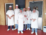 Christophe Astori, moniteur d’ateliers de cuisine, entouré de 6 jeunes portant blouse et charlottes