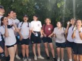 Des jeunes participant au séjour du SNU 2022 se regroupent pour un cri de groupe, en souriant et en chantant.