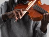 image centrée sur le buste et les bras d'un musicien jouant du violon