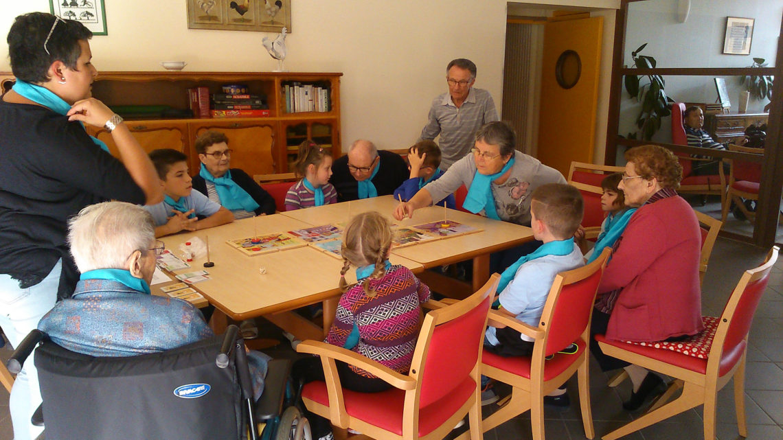 Atelier Adapa : des personnes âgées sont réunies autour d'une table avec 6 enfants et jouents ensemble à un jeu de société