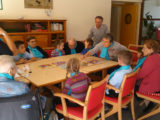 Atelier Adapa : des personnes âgées sont réunies autour d'une table avec 6 enfants et jouents ensemble à un jeu de société