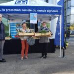 Stand "distribution anti-gaspi" de la MSA : quatre personnes posent pour la photo, dont deux tiennent des cagettes remplies de légumes