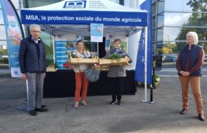 Stand "distribution anti-gaspi" de la MSA : quatre personnes posent pour la photo, dont deux tiennent des cagettes remplies de légumes