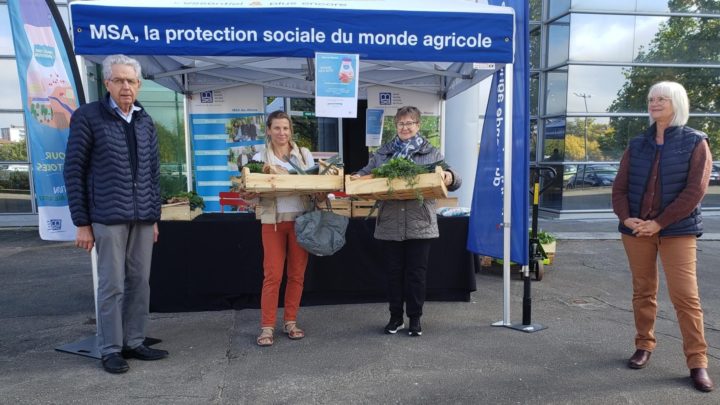 Stand "distribution anti-gaspi" de la MSA : quatre personnes posent pour la photo, dont deux tiennent des cagettes remplies de légumes