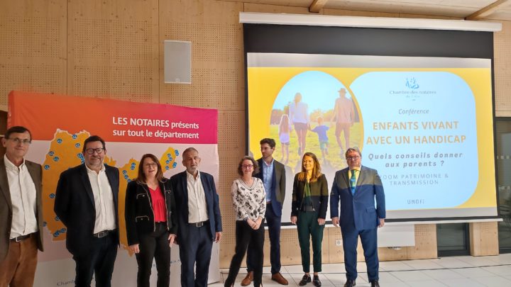 Intervenants, représentants et bénévoles posent devant l'affiche et la projection du support de la conférence sur le thème des questions successorales dans le cas d'enfants en situation de handicap