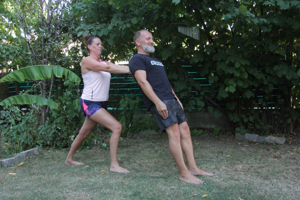 Aikido santé - posture : Une adulte en fente, bras tendus devant elle, retient un autre adulte qui se laisse tomber en arrière, en confiance, contre sa partenaire.