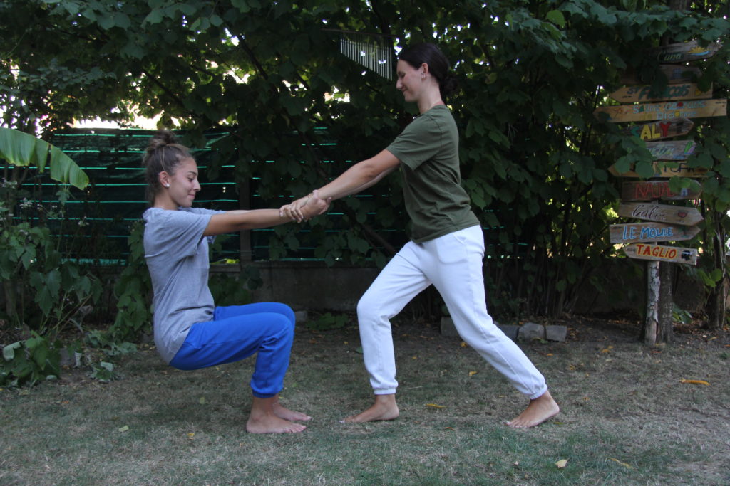 Aikido santé - posture : Deux jeunes se tiennent en équilibre par les poignets, l'une en fente et l'autre jambes pliées, en arrière