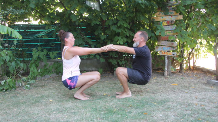 Aikido santé - posture : Deux jeunes filles se tiennent par les mains, face à face, en position de la chaise ou squat profond (assises dans le vide)