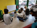 Parents et enfants sont accroupis pour jouer au LAEP Jeunes Pousses à Bourg-en-Bresse