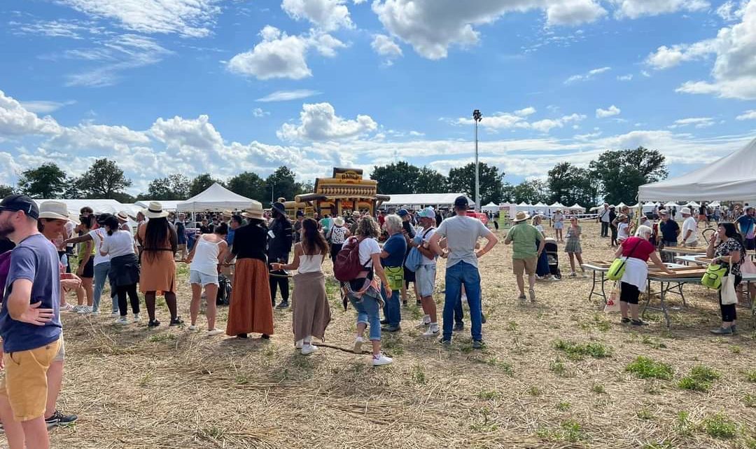 La fête annuelle de l'association des agriculteurs sourds de France a eu lieu cette année dans l'Ain, et a attiré beaucoup de monde. on voit des centaines de personnes présentes dans un champs sous le ciel bleu