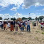 La fête annuelle de l'association des agriculteurs sourds de France a eu lieu cette année dans l'Ain, et a attiré beaucoup de monde. on voit des centaines de personnes présentes dans un champs sous le ciel bleu