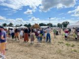 La fête annuelle de l'association des agriculteurs sourds de France a eu lieu cette année dans l'Ain, et a attiré beaucoup de monde. on voit des centaines de personnes présentes dans un champs sous le ciel bleu