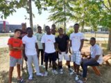 un groupe de jeunes migrants adolescents, mineurs non accompagnés (MNA) sourient pour la photo. ils sont dans un parc en été.