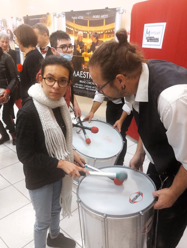 Culture et santé : À l’IME La Côtière, une jeune fille fait des percussions sur le tambour d'un musicien de la compagnie des Zurbamateurs pendant la représentation de batucada préparée.